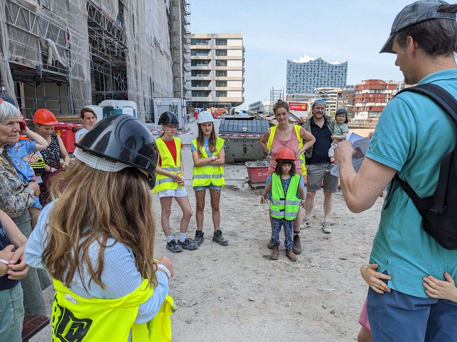 Familien mit Bauhelmen bei einer Führung über die Urbaneo-Baustelle in der Hamburger HafenCity